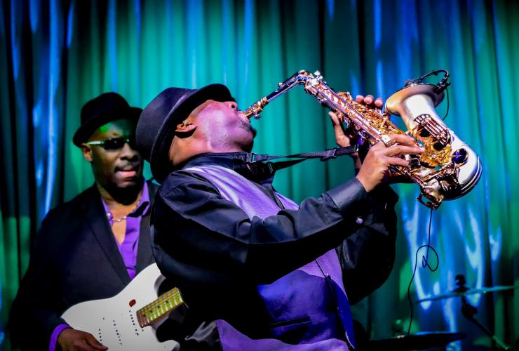 black musician playing saxophone on stage nightclub