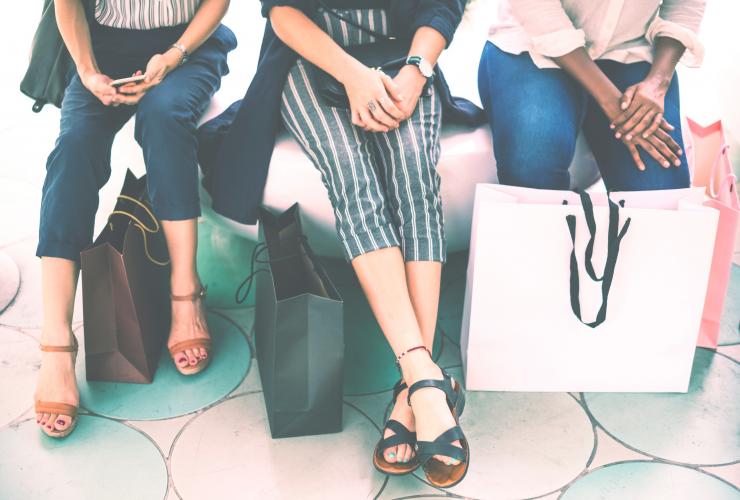 three woman sitting with shopping bags