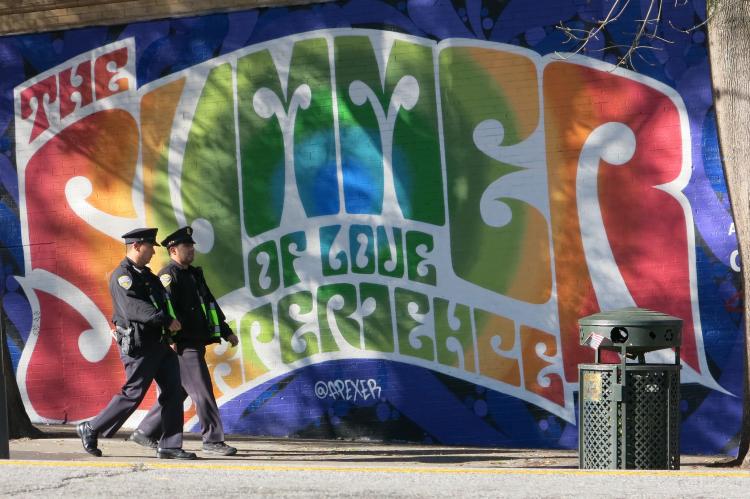 Picture of the text "Summer of Love" in rainbow letters with two police officers walking by on the sidewalk.